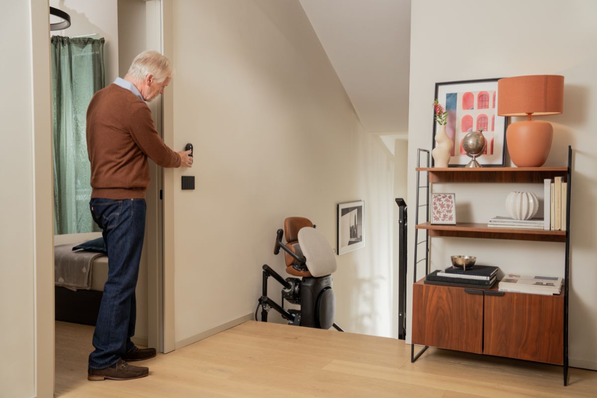 Homme utilisant la commande pour déplacer le monte-escalier Stannah Joya jusqu’en haut de l’escalier.