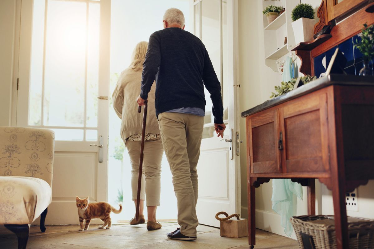 Couple senior quittant son domicile avec une canne de marche