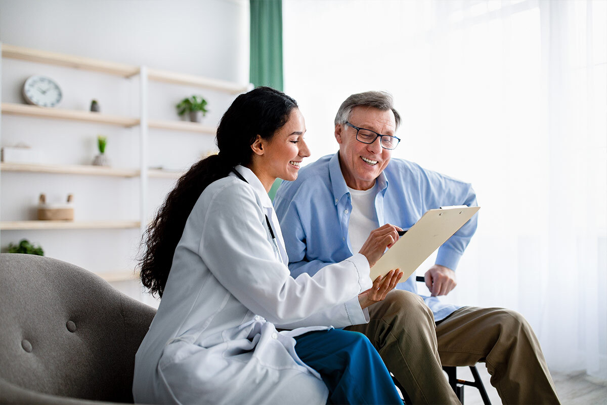 Médecin souriante qui consulte un dossier avec un homme senior, dans un salon lumineux